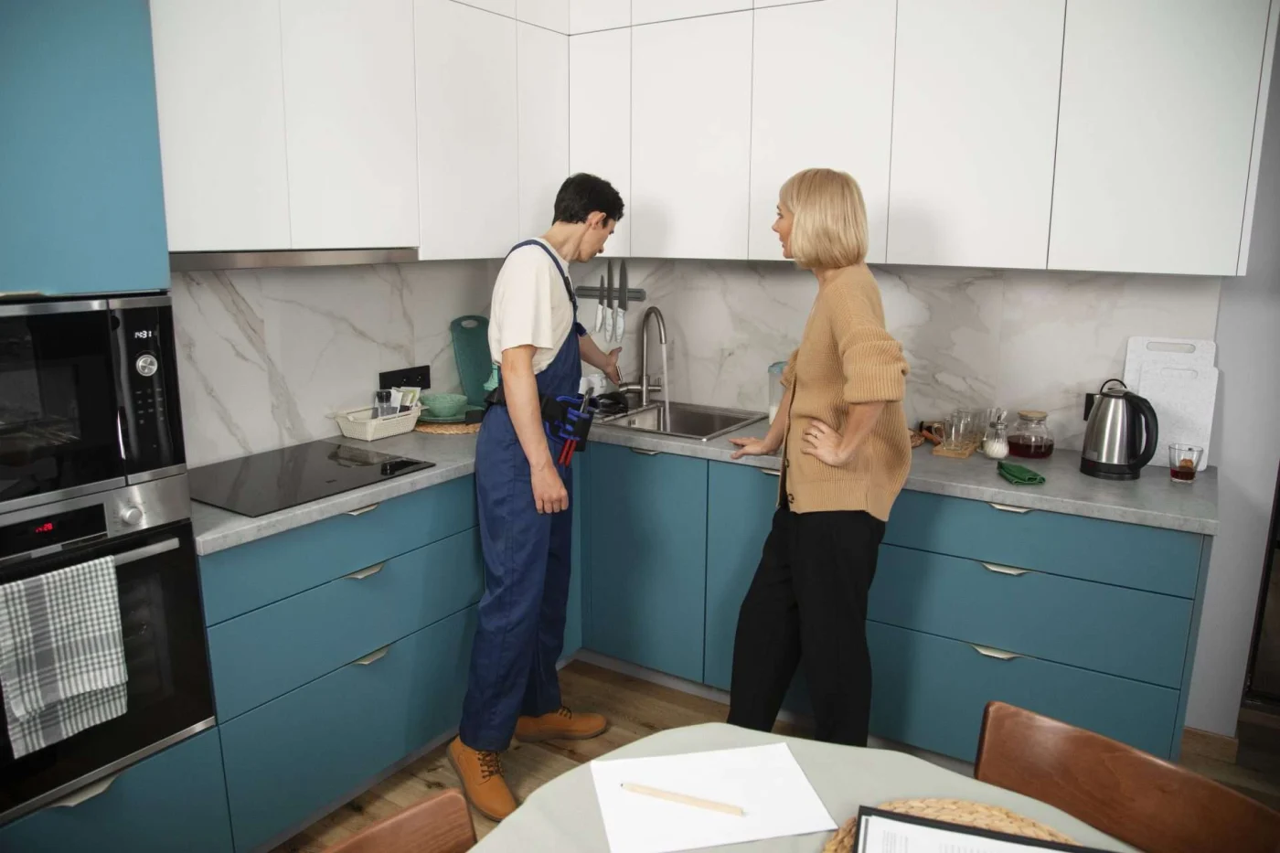Plumber working with homeowner in kitchen, illustrating steps and expectations during a remodel