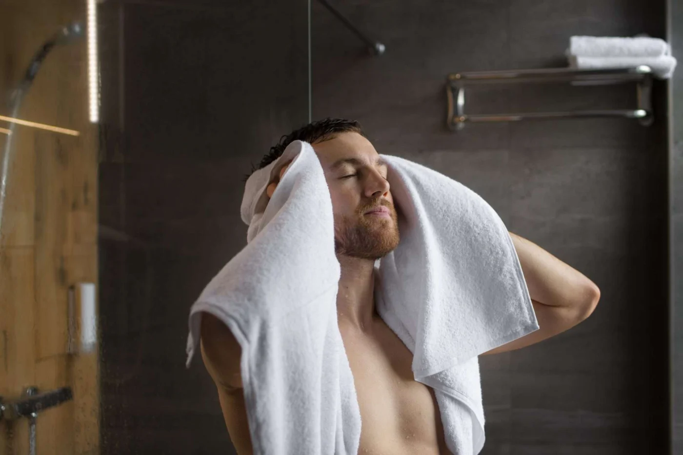 Man wiping with towel in bathroom, symbolizing safety and comfort improvements in shower or bathtub areas