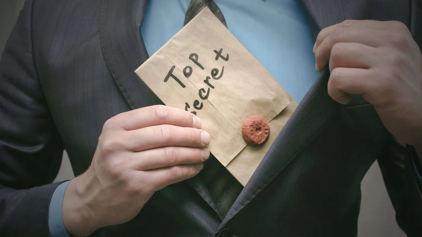 Close up on man in suit pulling “Top Secret” folder out