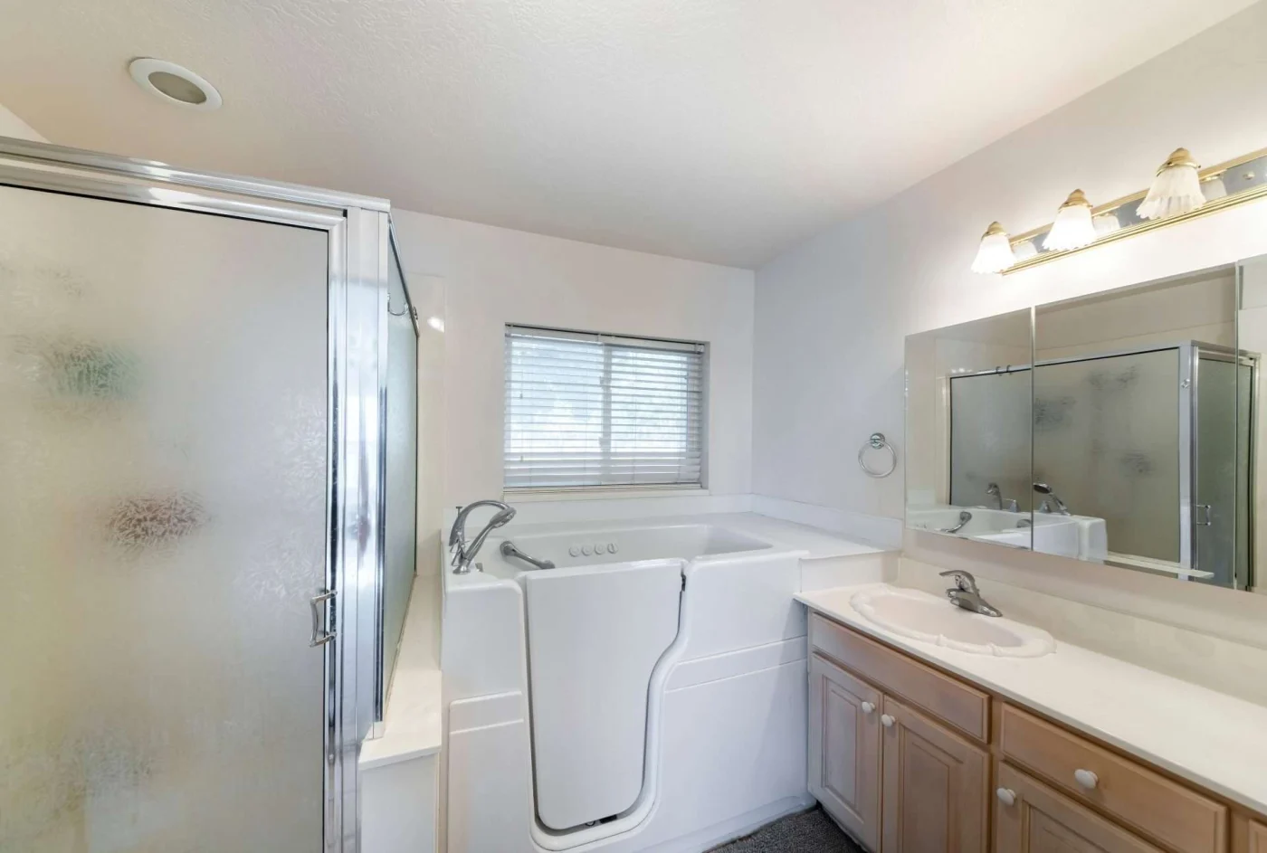 White walk-in tub next to a walk-in shower and large white vanity