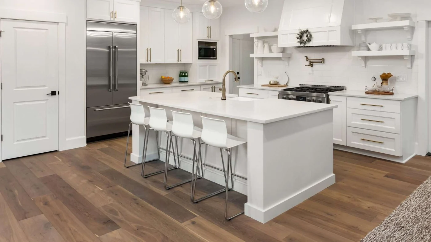 A kitchen with brown wood floors and white countertops and cabinets