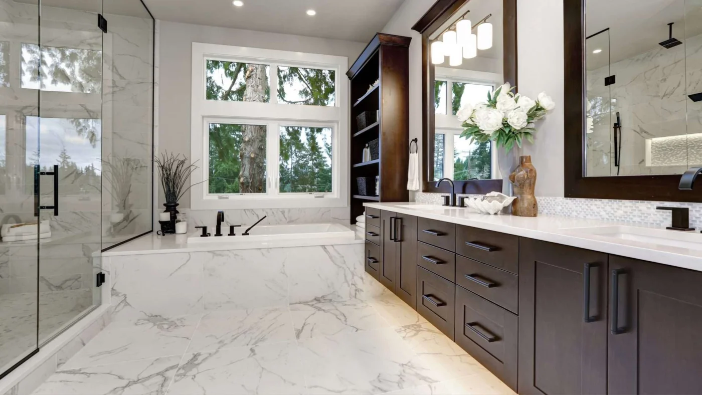 A bathroom with a tub and a walk-in shower that has a brown vanity and white and gray flooring