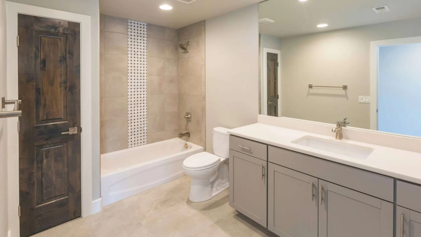 A simple bathroom with a white tub and a gray vanity