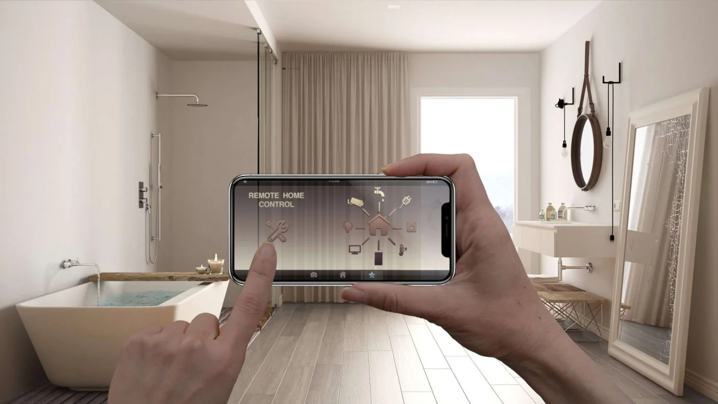 Hands holding a smartphone in front of a neutral bathroom with a tub, shower, sink, and large mirror