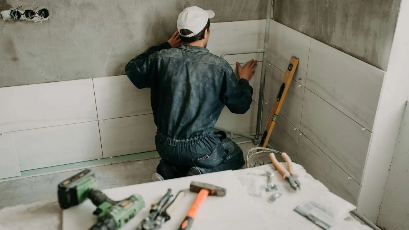 A workman tiling a shower