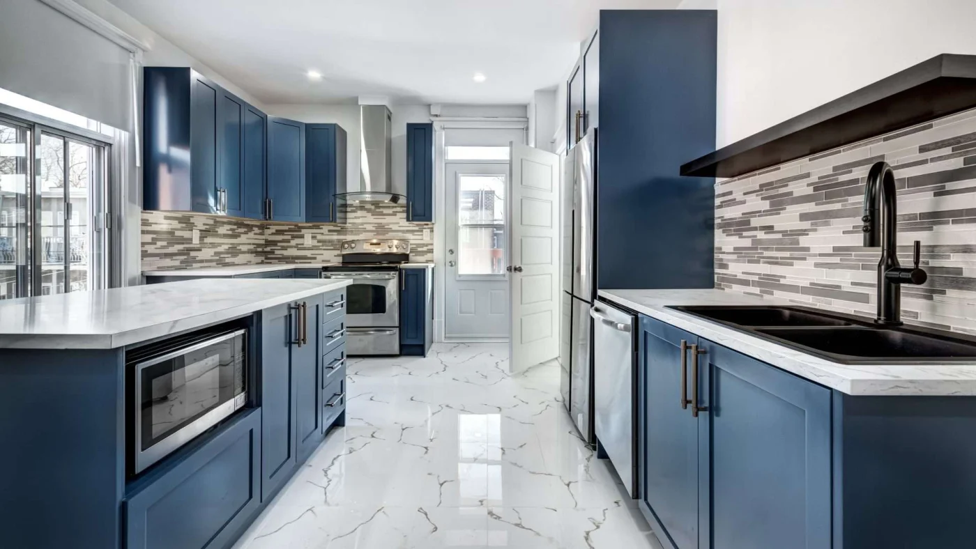 A kitchen with blue cabinets, white countertops, a black sink, and stainless steel appliances