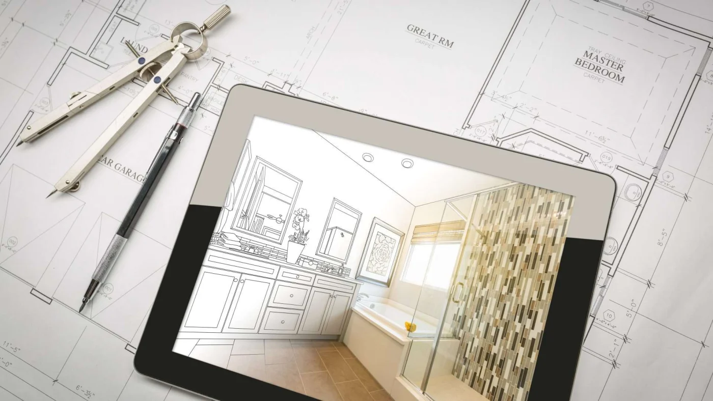 A tablet with a half-sketched bathroom rests on top of house plans with design tools lying nearby
