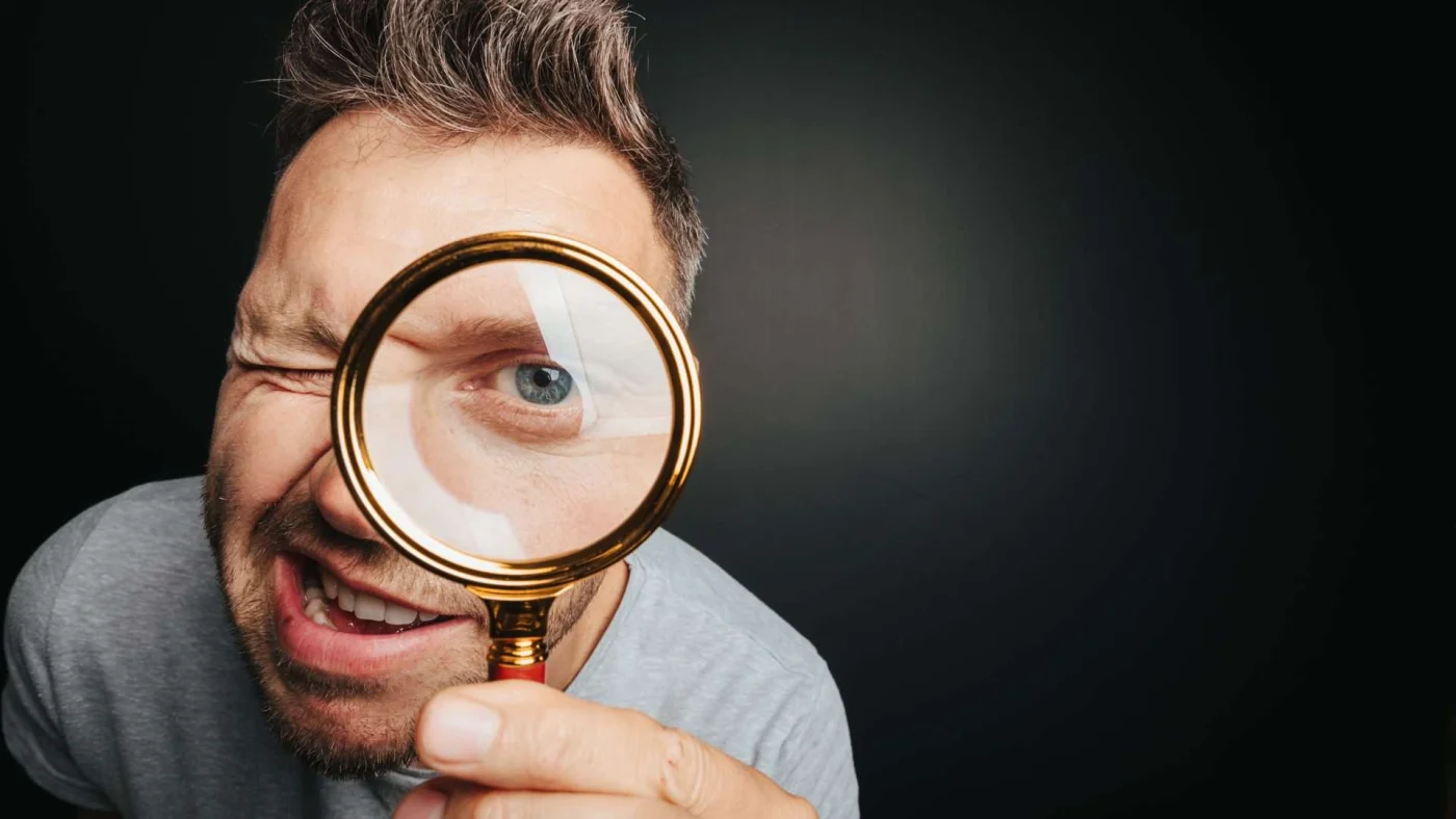A man looks through a magnifying glass
