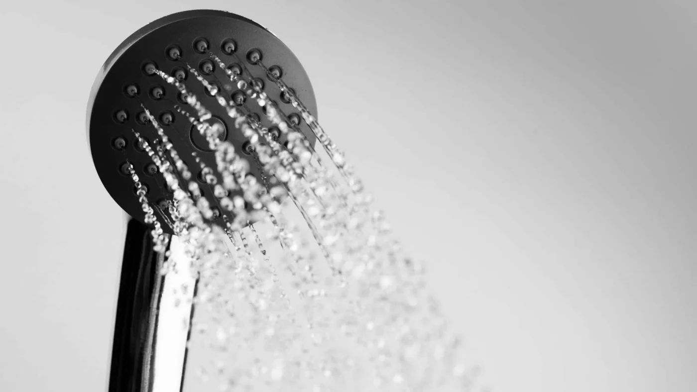 Close-up of black showerhead with water flowing out of it