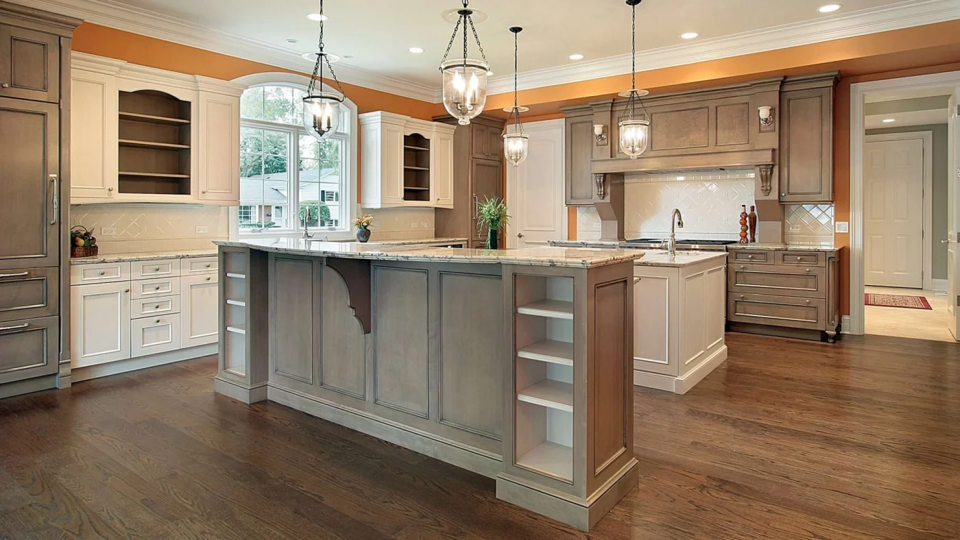 Beautifully remodeled kitchen with wood flooring, white and brown cabinets, and hanging light fixtures