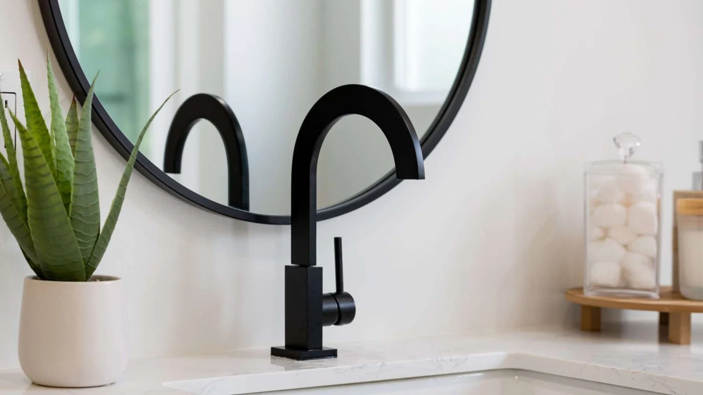 Close view of a matte black gooseneck faucet with matching hardware in a beautiful bathroom