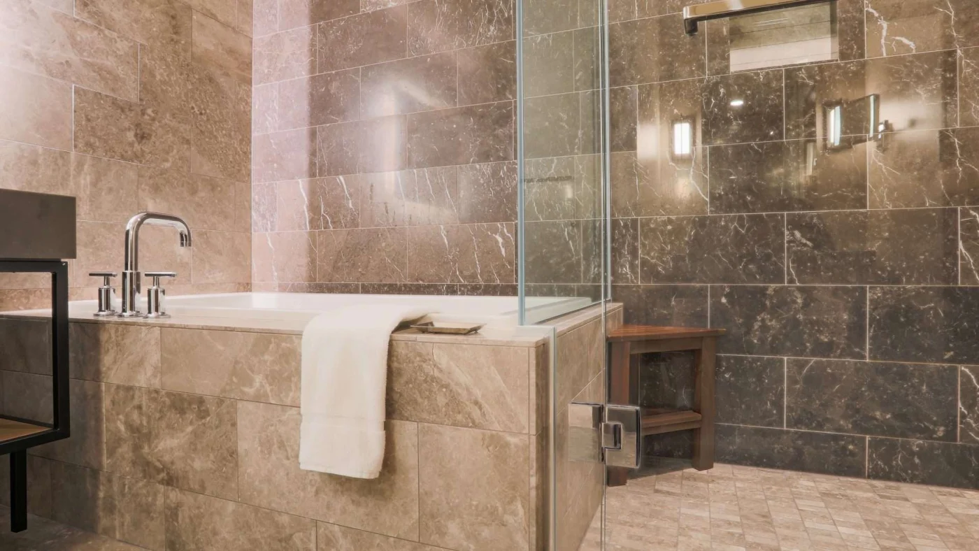 View of a modern bathroom with elegantly tiled bathtub, shower, and floor
