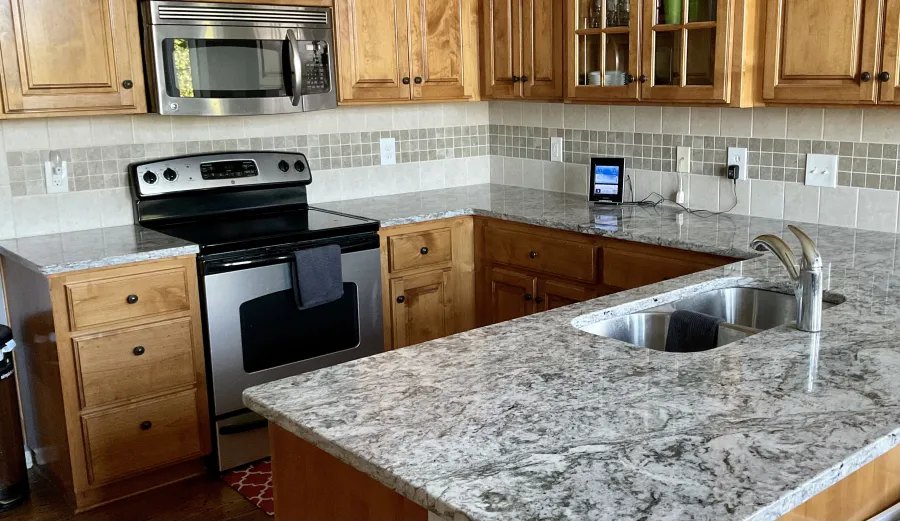 Dining room with light blue interior, flat screen TV, white cabinet, and table with granite countertop