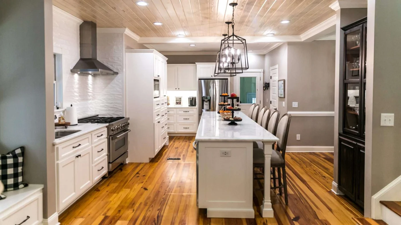 Newly remodeled kitchen in Kansas City, MO with beautiful hardwood flooring, marble countertops, and white cabinetry