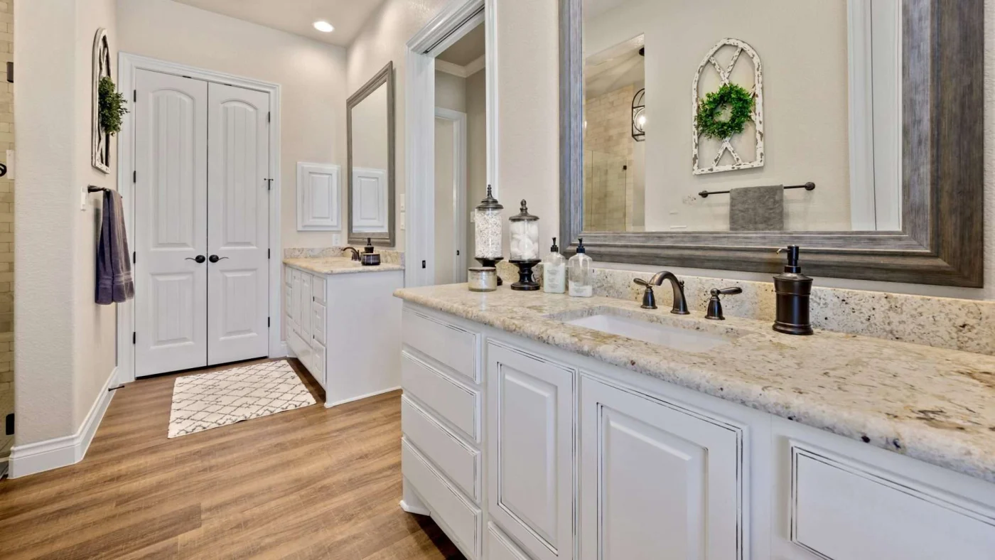New modern bathroom remodel with wood flooring and dual sinks with stone countertops and rustic wooden framed mirror
