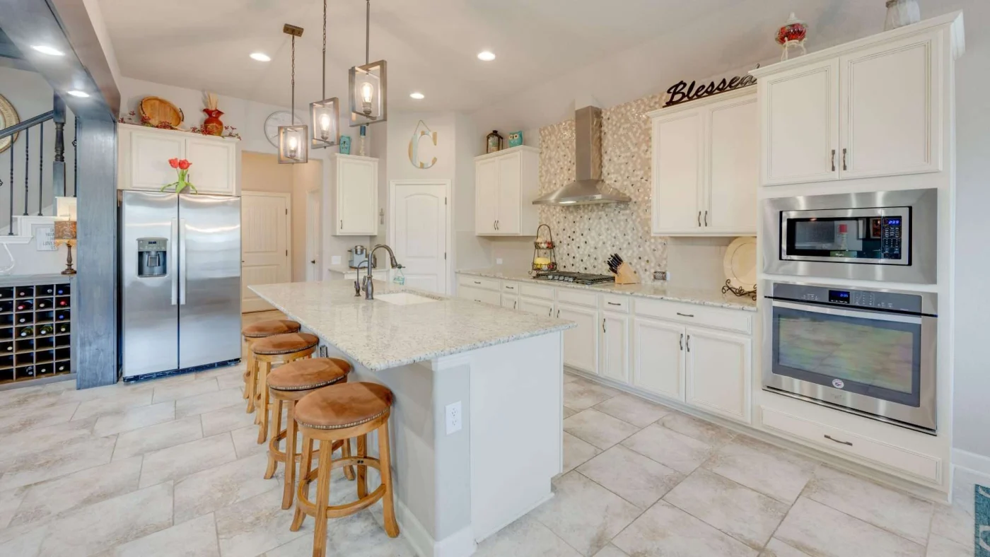 Modern kitchen remodel with tile flooring, white cabinets, bright stone countertops and hanging lights