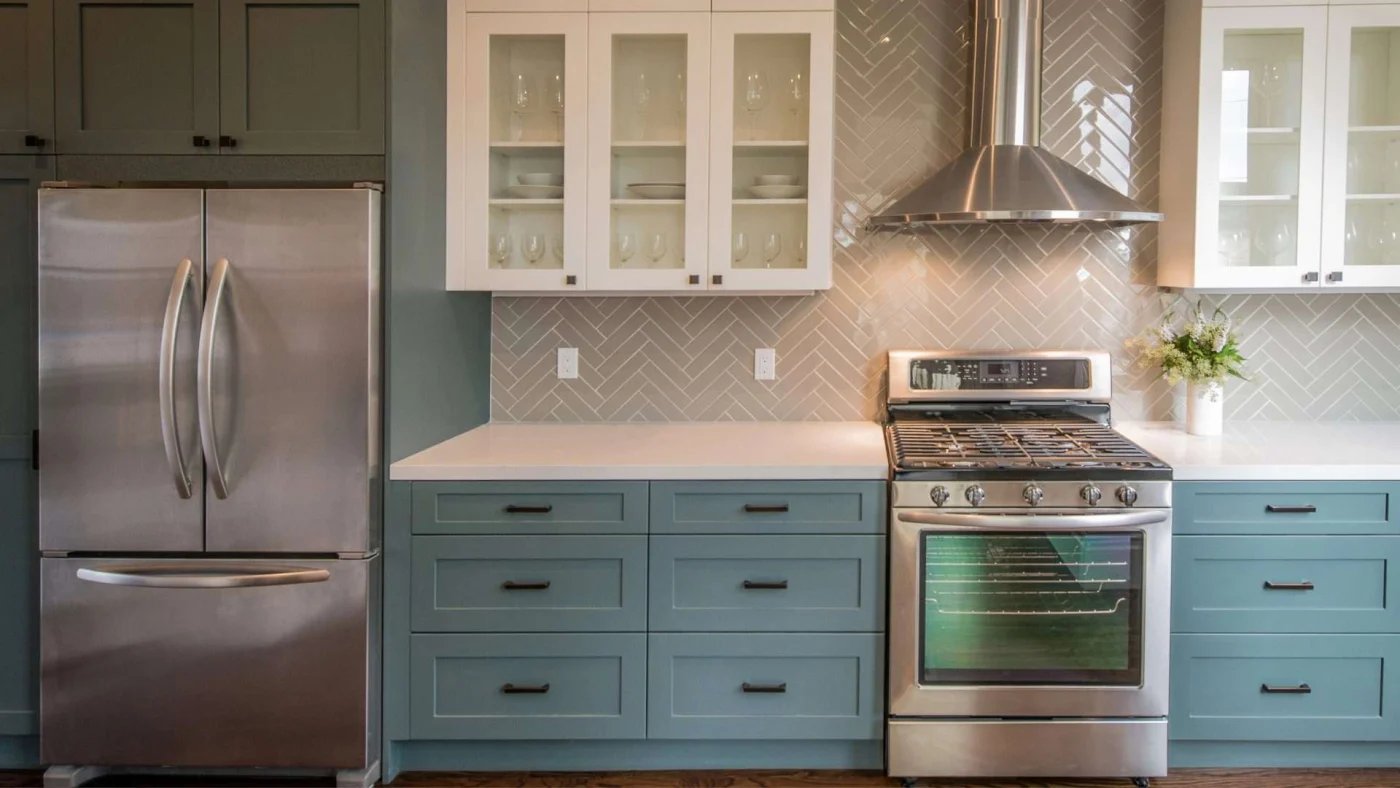 A kitchen with blue and white cabinets, silver appliances, and white countertops