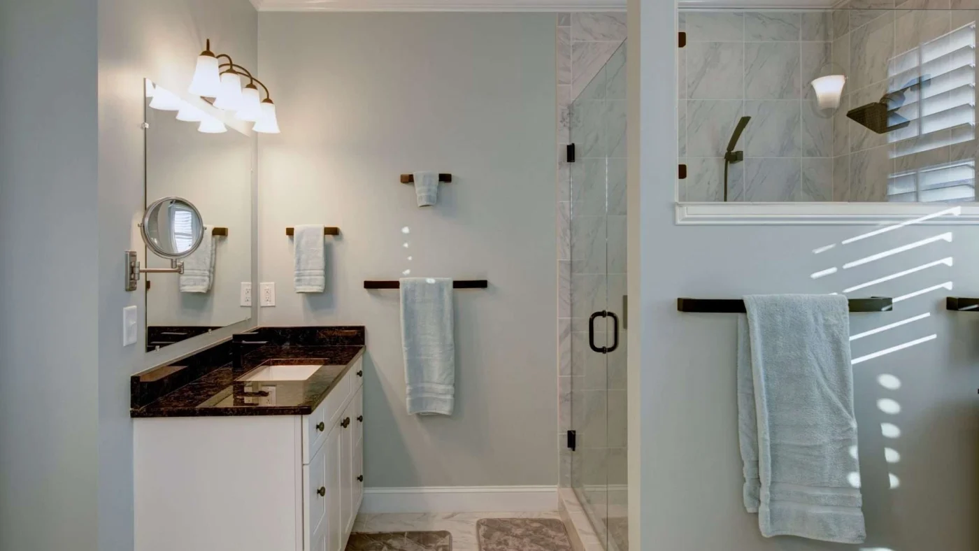 A bathroom with a white vanity, black countertop, and walk-in shower