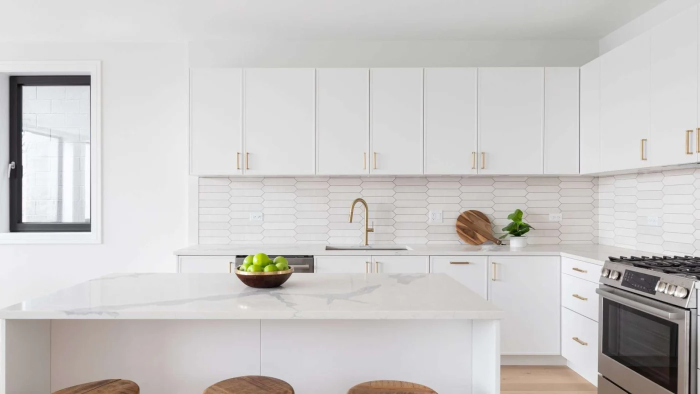 View of a white-themed contemporary kitchen with a central island and a unique tile backsplash