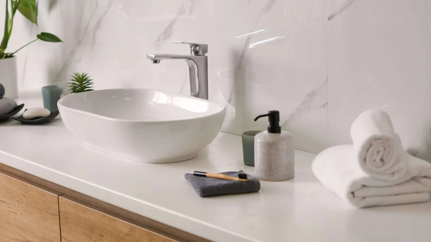 Close, angled view of a bowl sink on a wood vanity with a tile backsplash