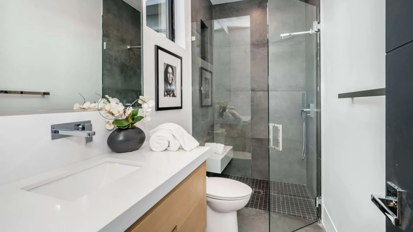 Modern bathroom remodel with glass shower, marble cabinets, and large vanity mirror