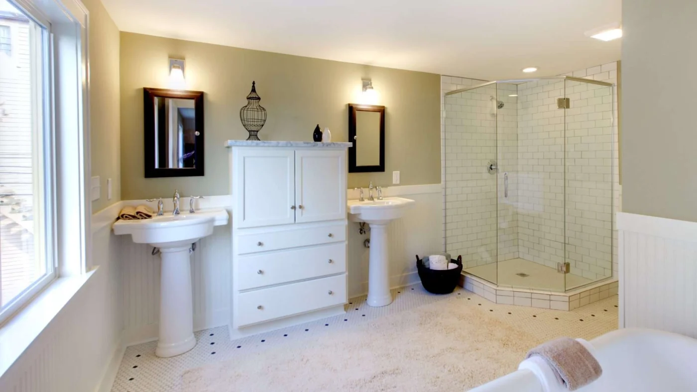 Newly remodeled bathroom with white tile flooring and corner shower with glass shower door