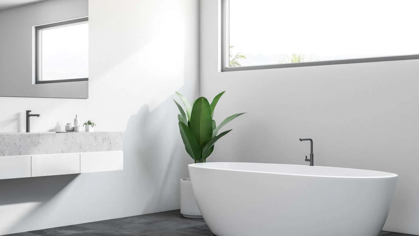 View of a sleek modern bathroom with a freestanding tub and a vanity with a concrete top