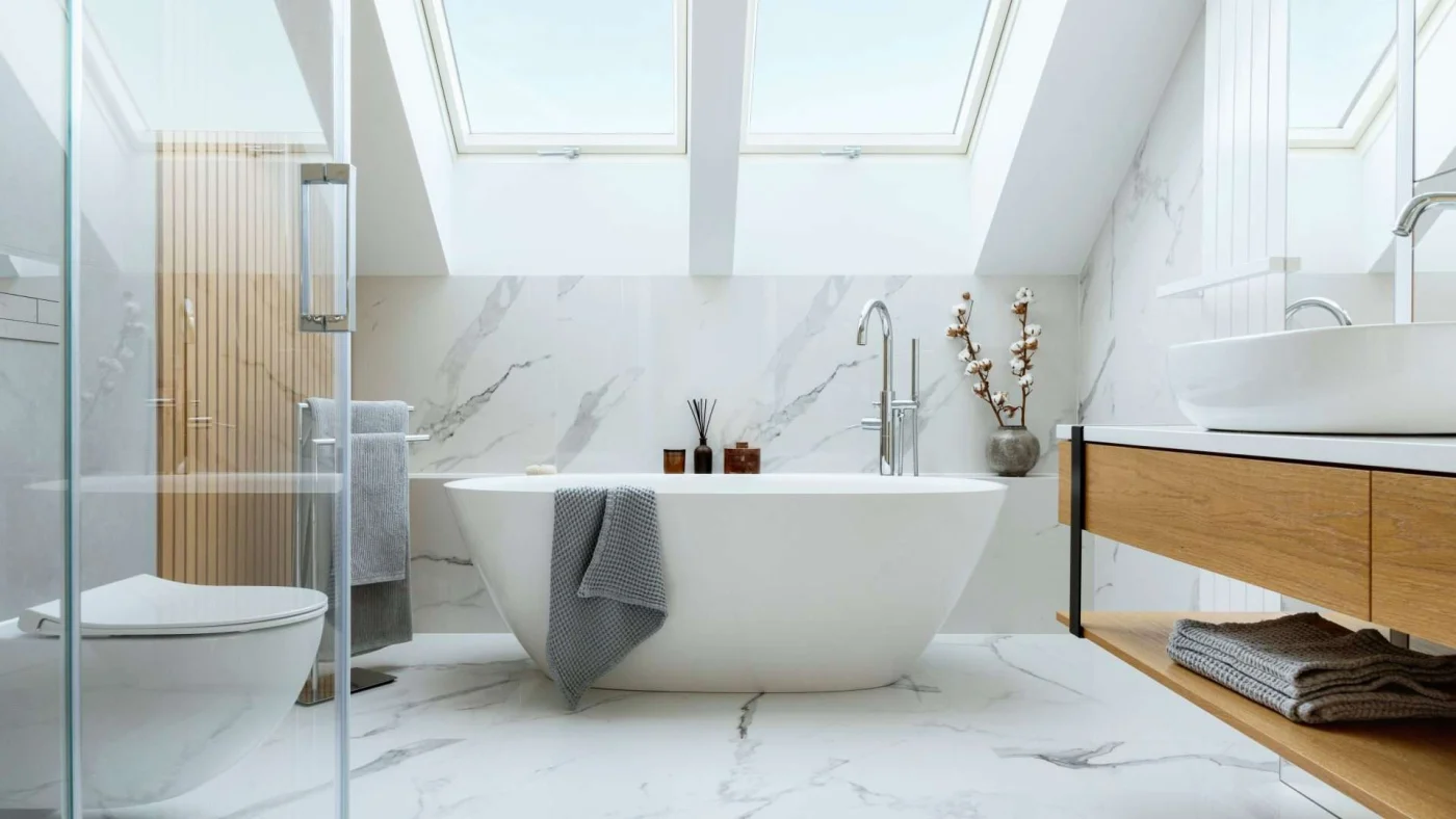 Interior view of a beautiful bathroom centered on a standalone bathtub under a large, angled skylight