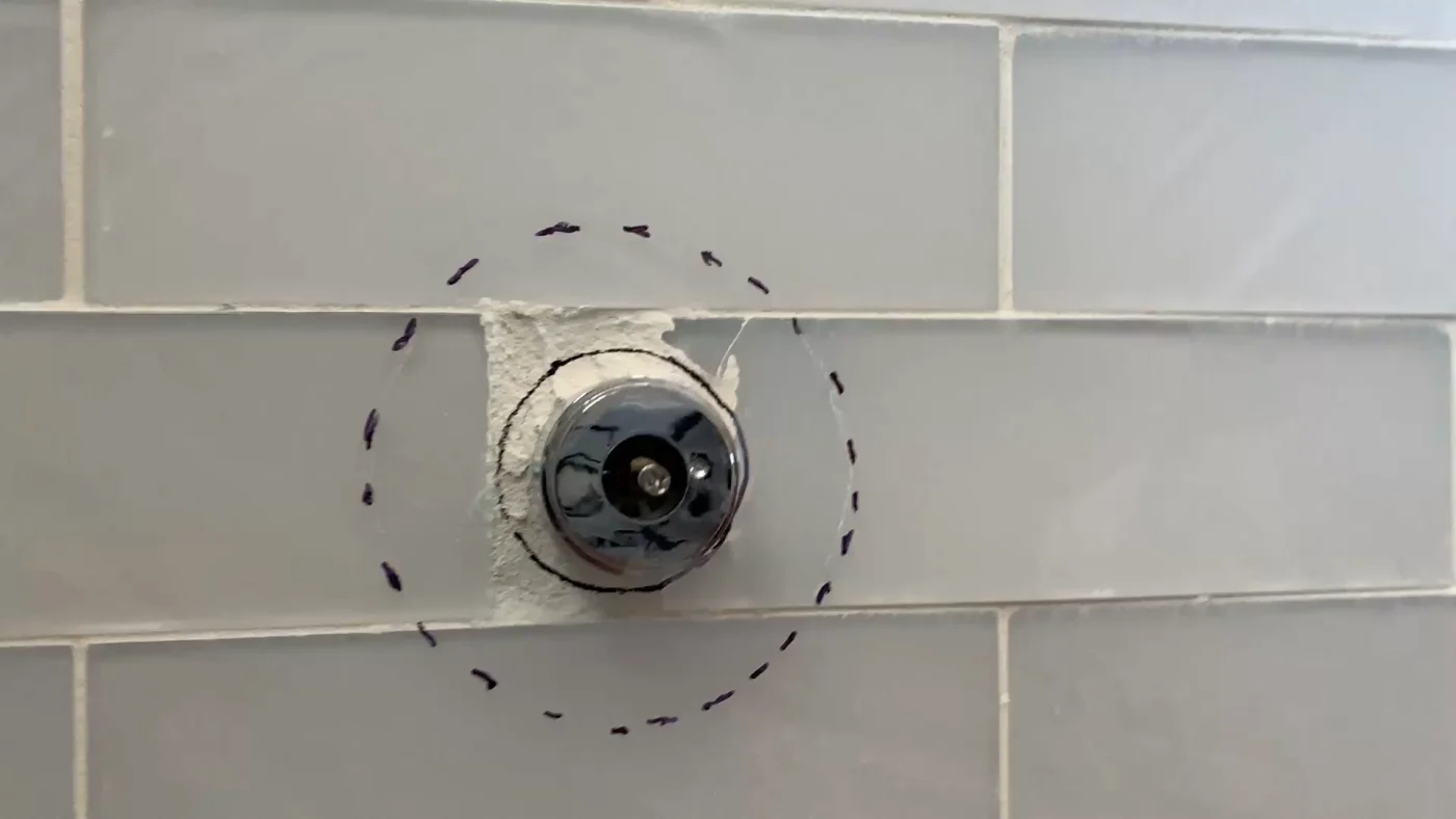 Shower valve on a tile wall grouted messily