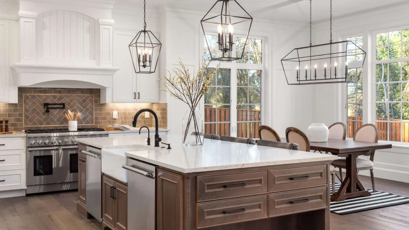 Angled view of a beautifully done kitchen with a dining area and huge, quartz-topped center island