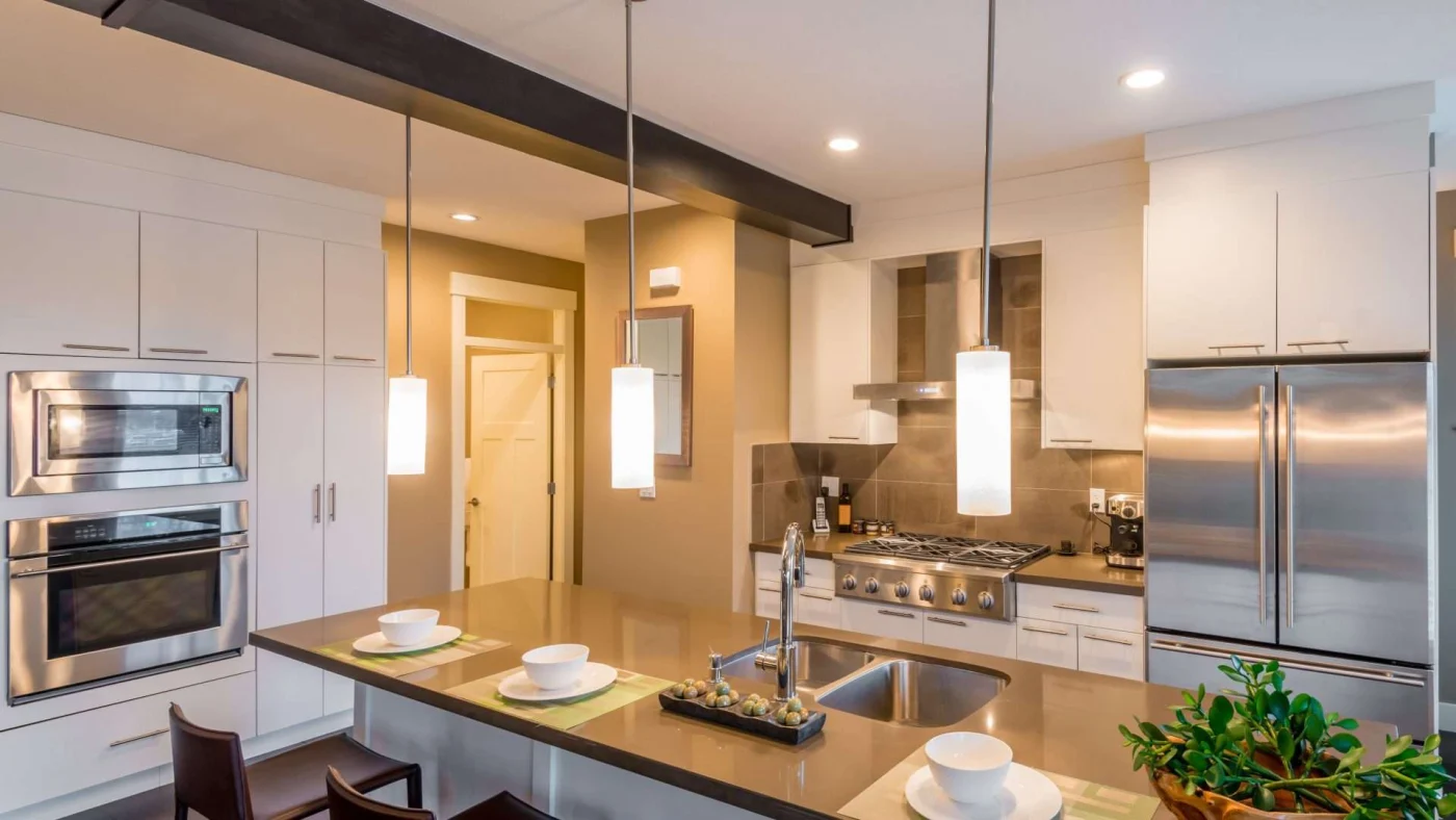 Angled interior view of a nicely appointed with pendant lights hanging over a central island with a built-in double sink