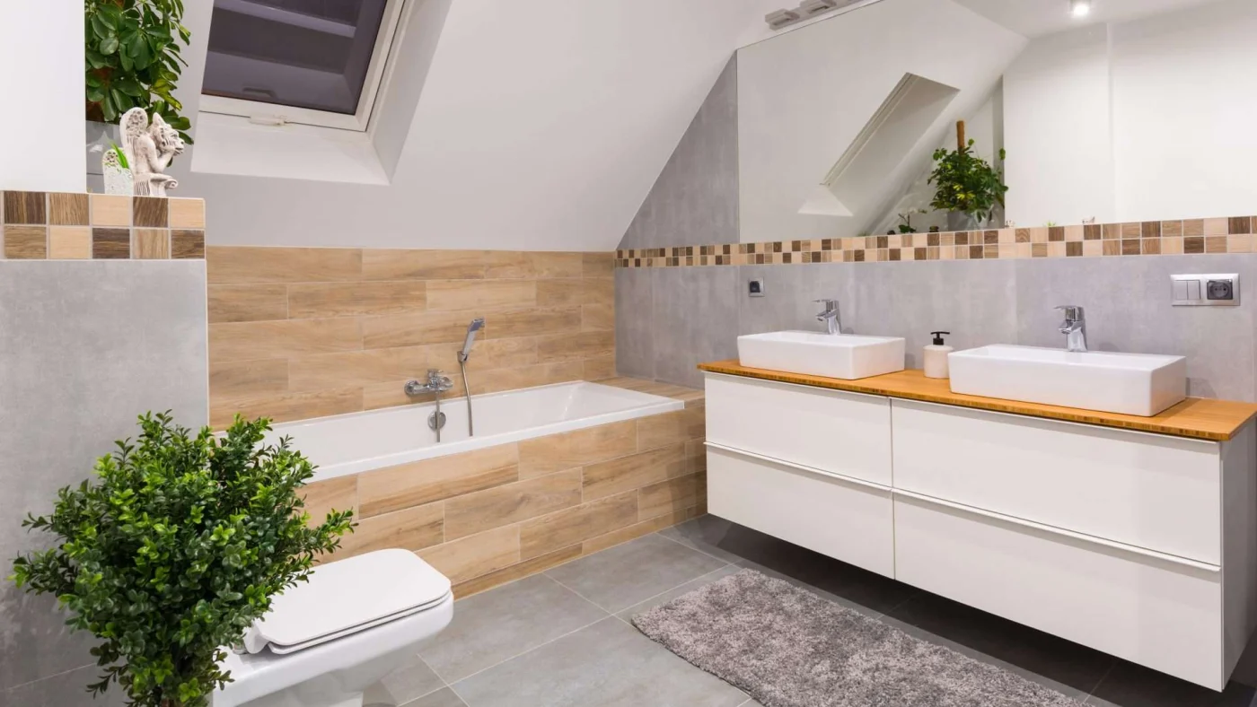 A bathroom with a double-sink vanity and decorative wood paneling around the bathtub