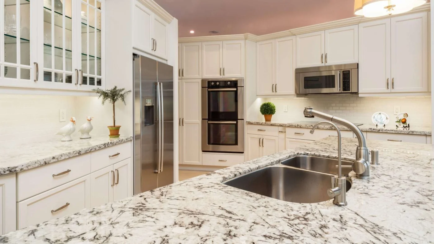 Remodeled kitchen with large stone countertops and lots of white cabinetry