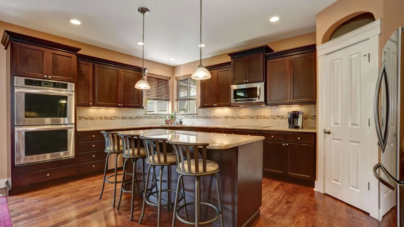 A kitchen with dark brown cabinets, lighter countertops, and stainless steel appliances