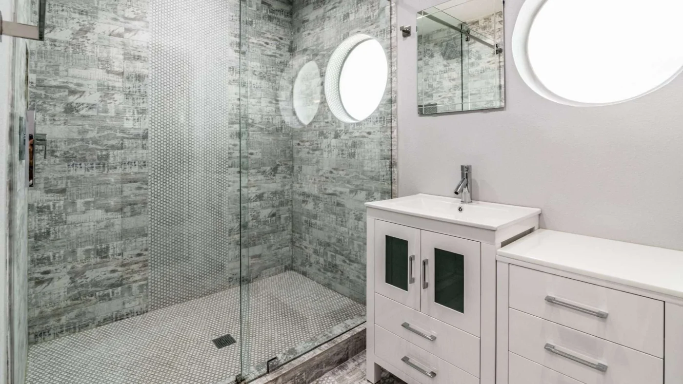 A bathroom with gray shower surrounds and a white vanity