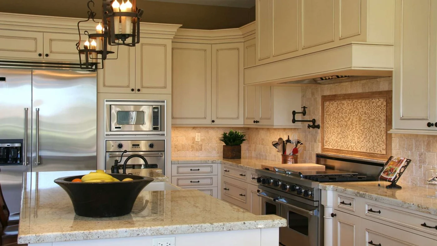 A kitchen with cream cabinets, an island, and stainless steel appliances