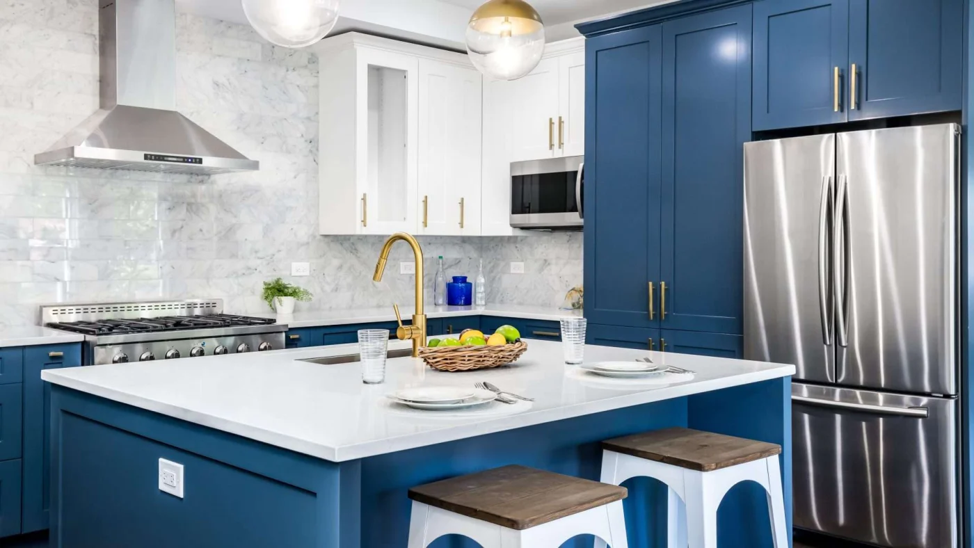 A kitchen with bright blue cabinets, stainless steel appliances, and white countertops