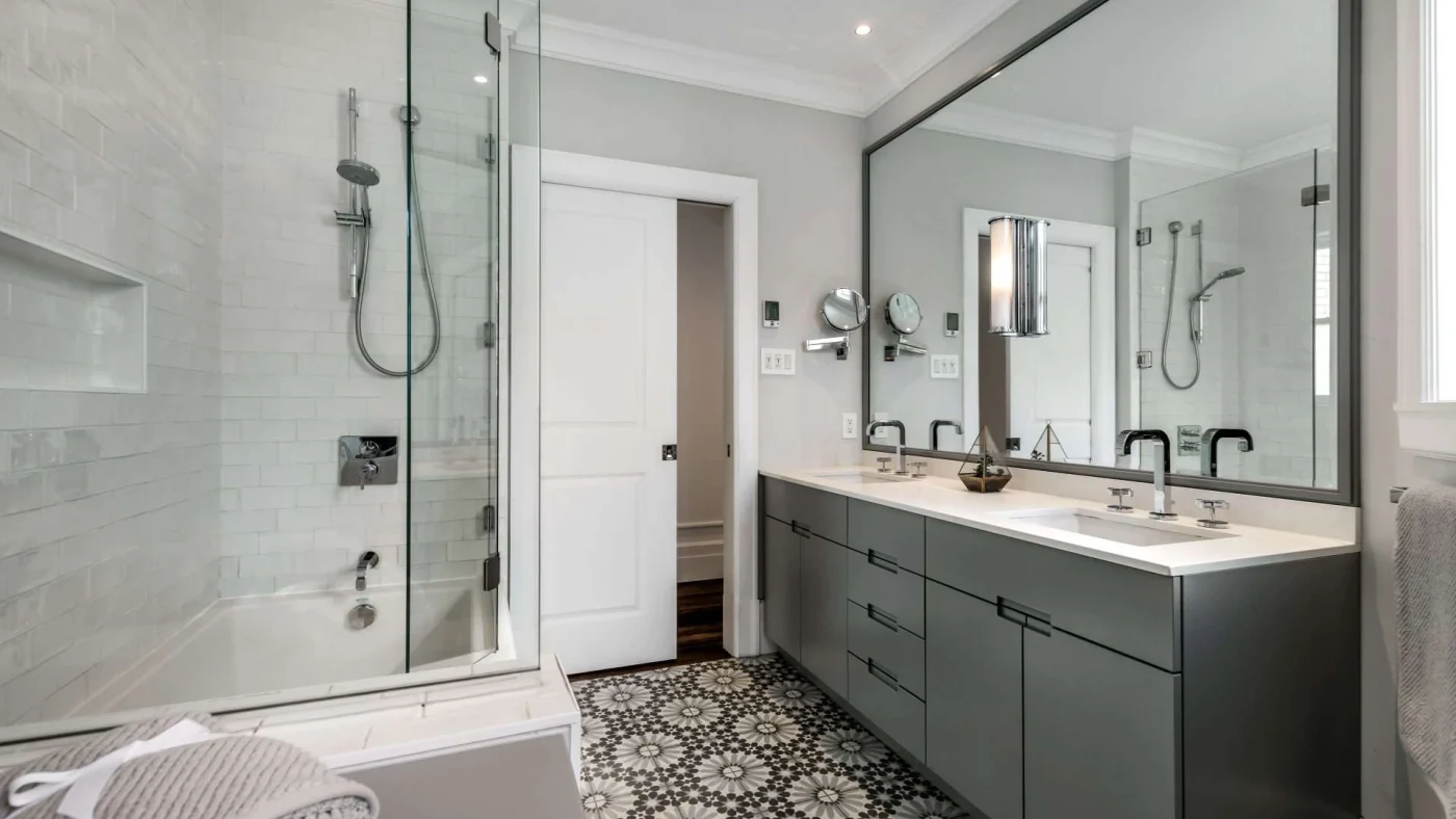 A bathroom with black cabinets, walk-in shower, and a large mirror
