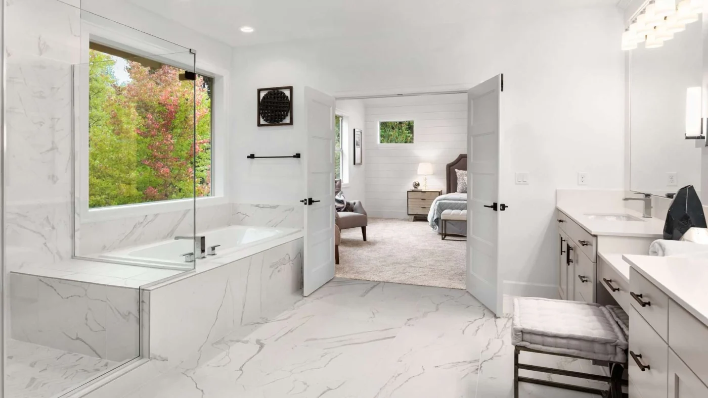 A white-themed primary bathroom leading into the primary bedroom
