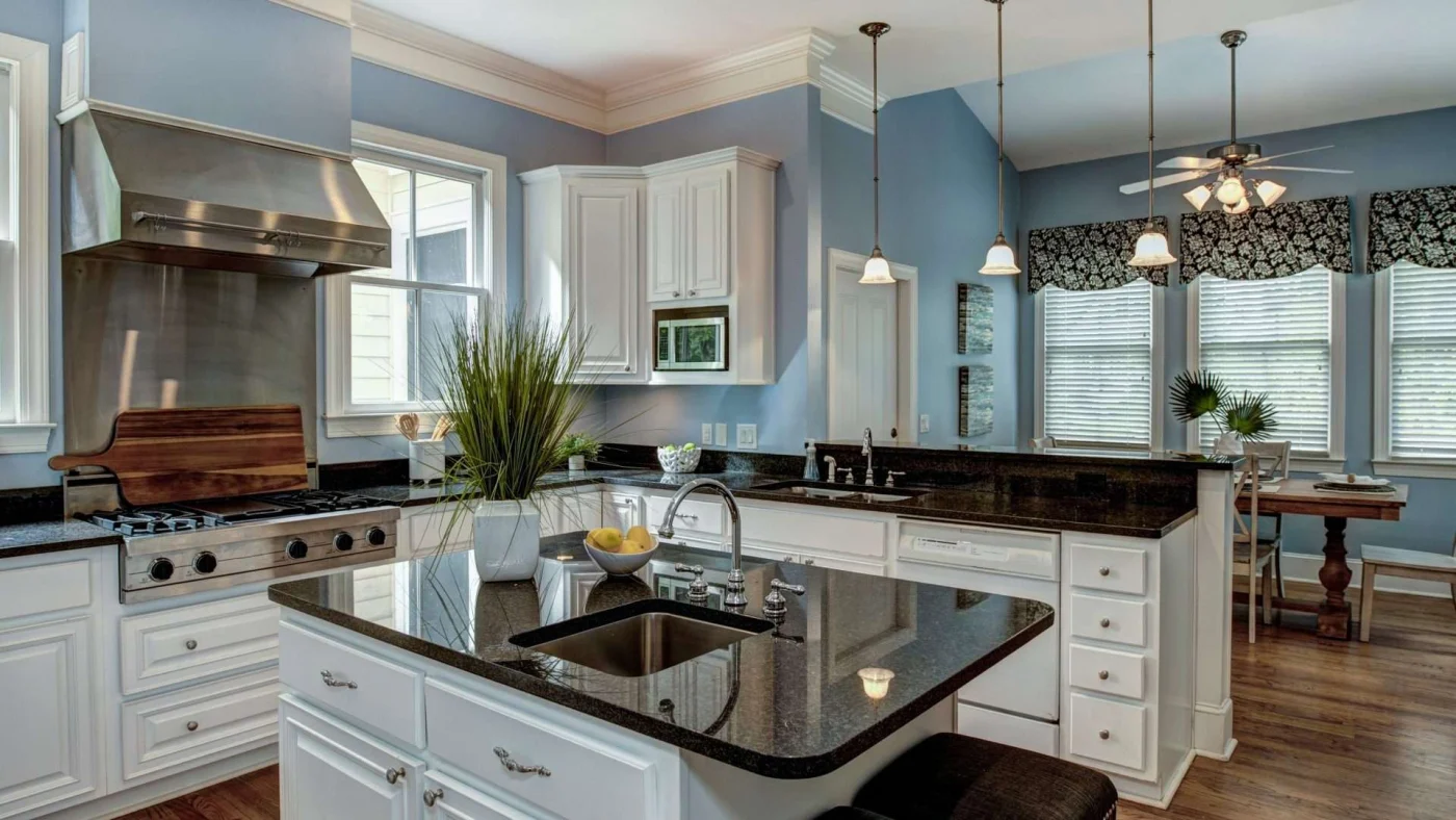 A kitchen with white cabinets, dark countertops, and stainless steel appliances