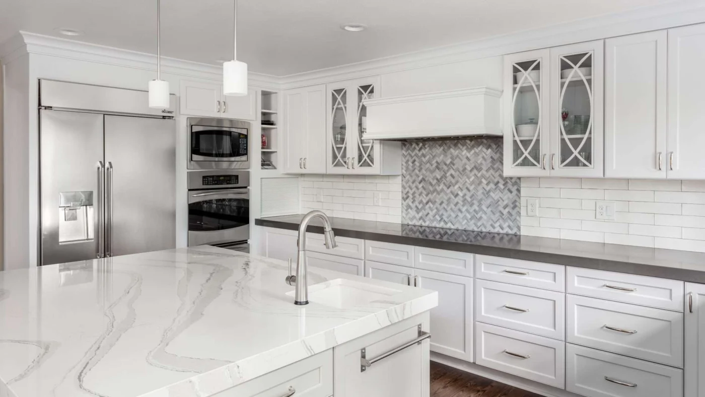 Modern kitchen with white cabinets, marble-colored countertops, and stainless steel appliances