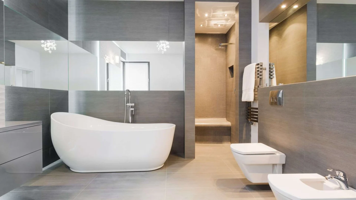 Frontal interior view of a beautifully remodeled bathroom with a bidet, freestanding tub, and a separate open shower stall in the background