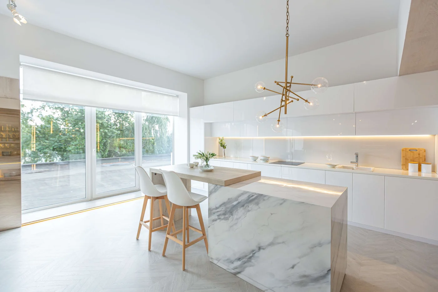 Spacious modern kitchen with white cabinets, marble island and sliding glass doors