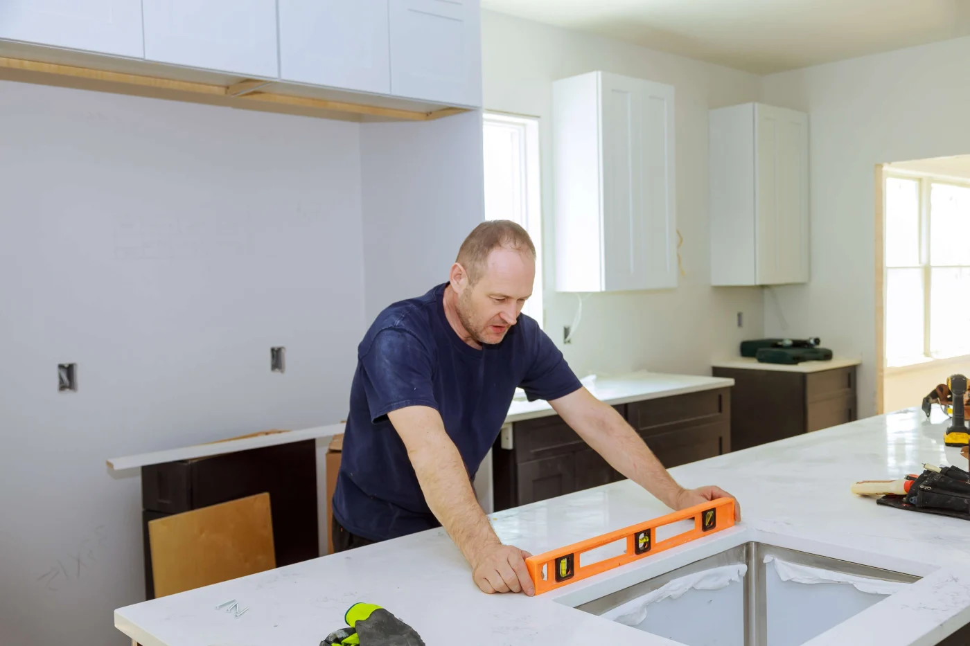 Kitchen in the process of being remodeled with worker ensuring countertops are level