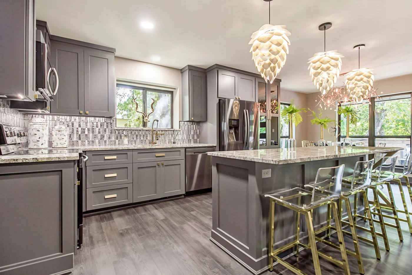 An image of an elegant, gray kitchen remodel highlighting gorgeous gray granite countertops covering the kitchen island in the center of the room and the countertops around the sink and underneath the cabinets.