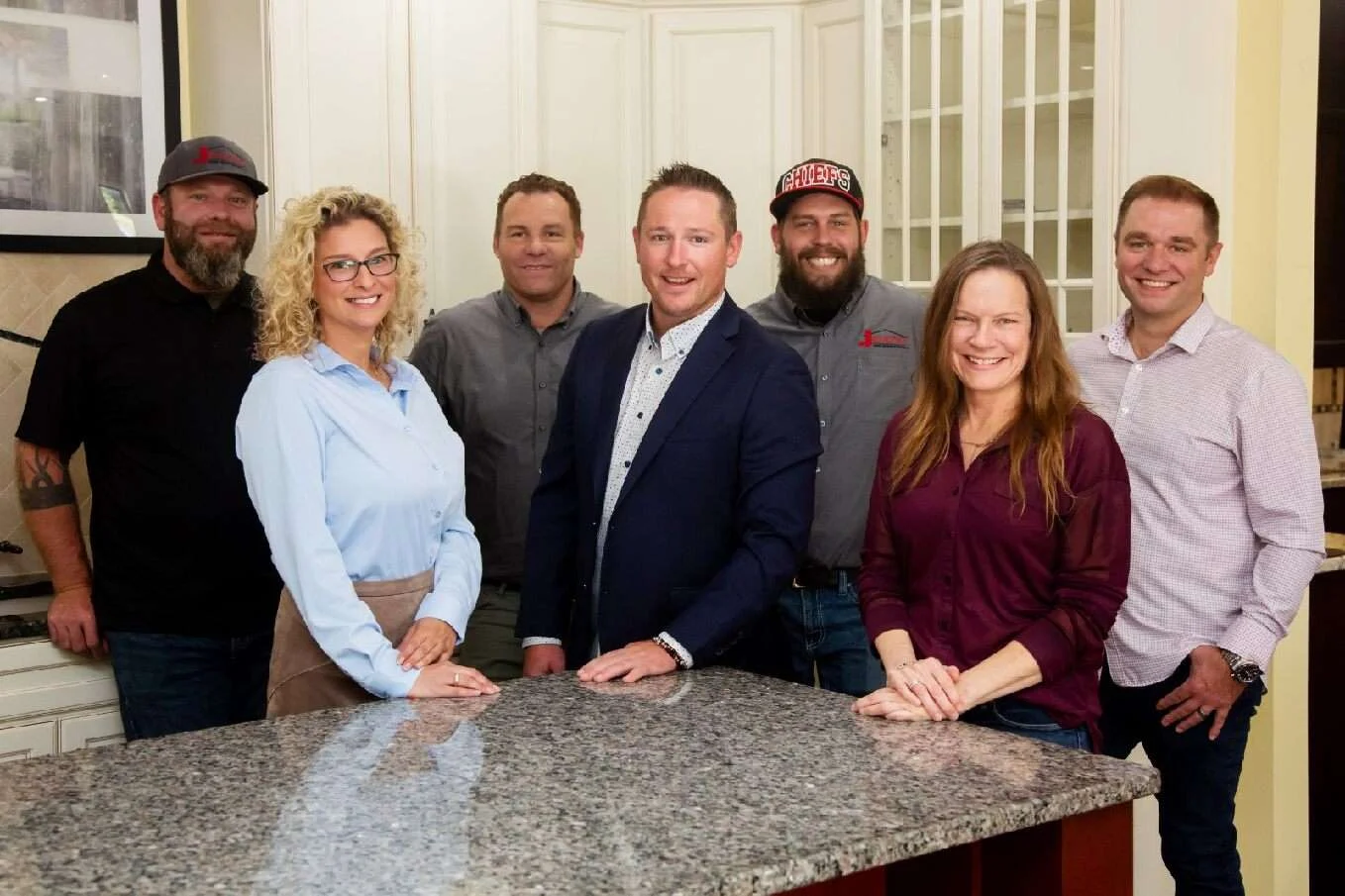 A friendly team of kitchen remodeling specialists gathers in a renovated kitchen.