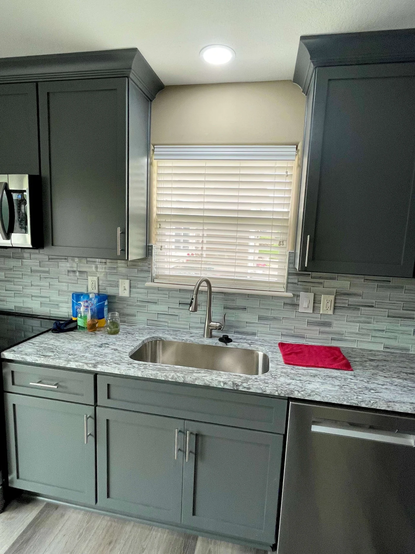 A modern open concept kitchen remodel with integrated appliances, a dark gray granite countertop and a dining area with a gray table and chairs.