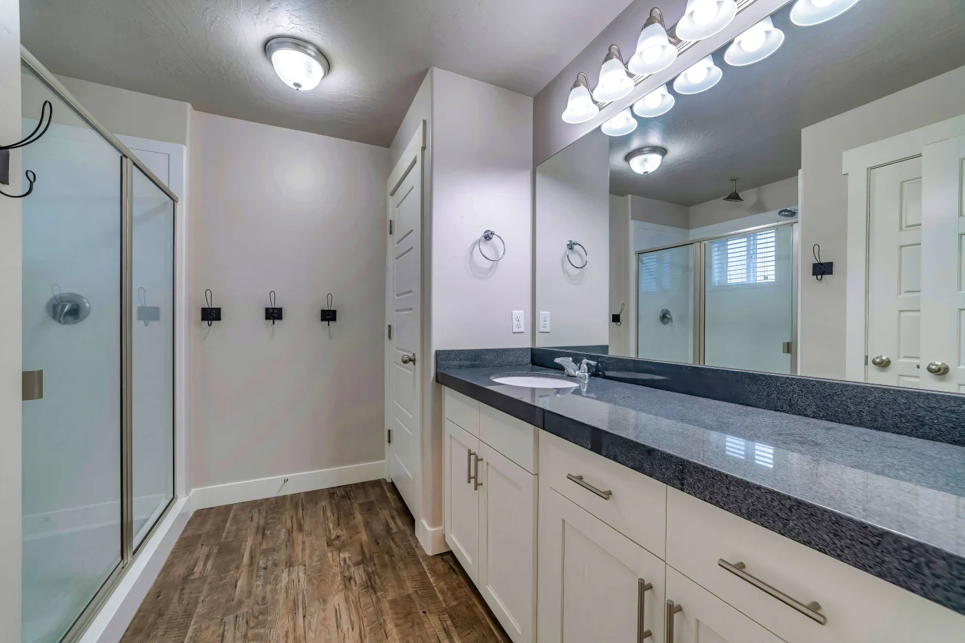 A bathroom with adequate lighting and white cabinets.