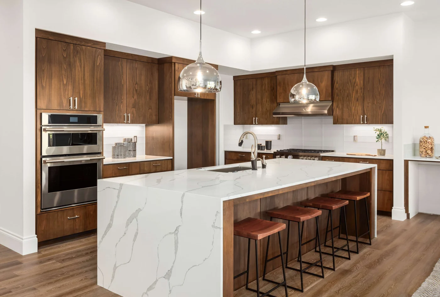 A kitchen with wooden cabinets, white countertops, stainless steel appliances, and overhead lighting.