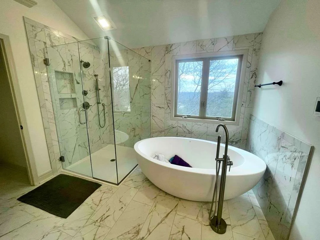 A white bathroom with an egg-shaped white bathtub, a walk-in shower with glass walls and door, and a window.